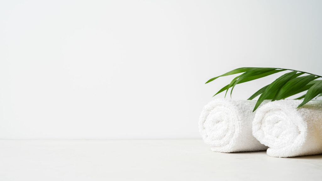 a white towel rolled up and a green plant